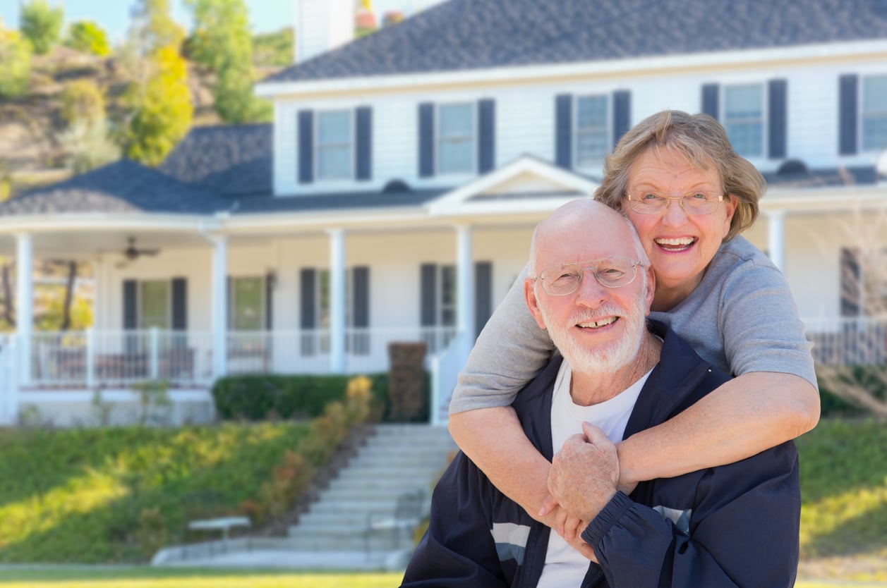 Happy Senior Couple in Front of House