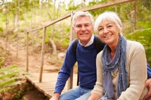 Happy senior couple sitting on a bridge in forest